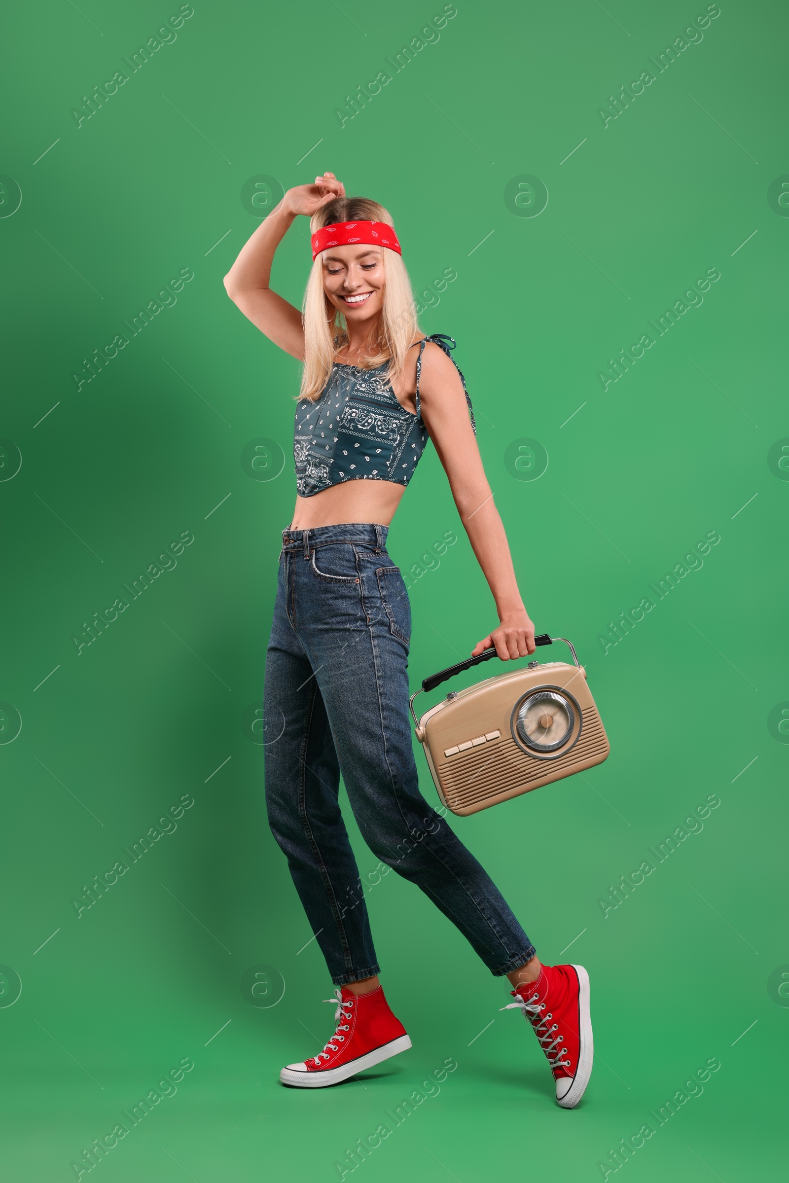 Photo of Happy hippie woman with retro radio receiver on green background