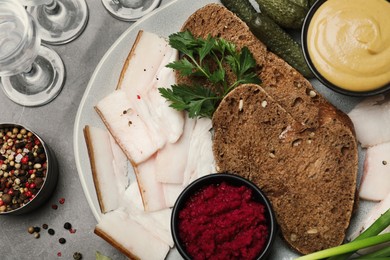 Photo of Tasty salt pork with rye bread and sauces served on grey table, flat lay