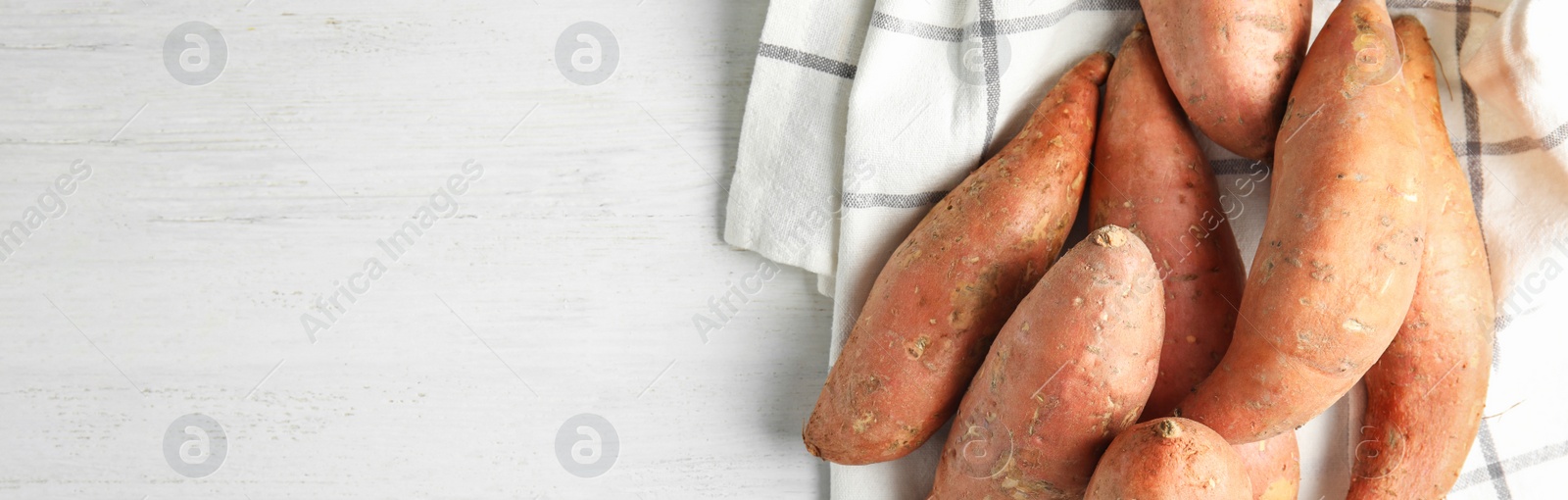 Image of Sweet potatoes and space for text on white wooden table, top view. Banner design