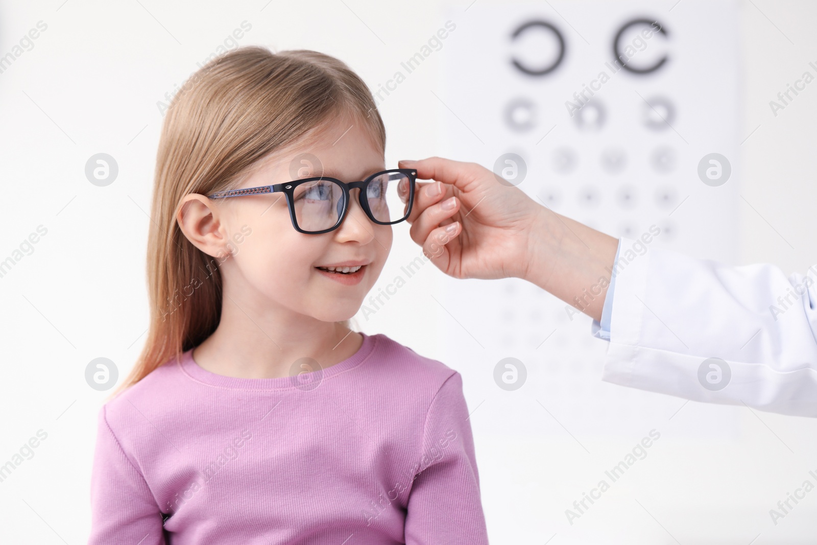 Photo of Vision testing. Little girl trying glasses at ophthalmologist office