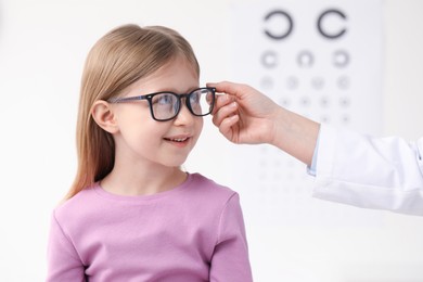 Vision testing. Little girl trying glasses at ophthalmologist office