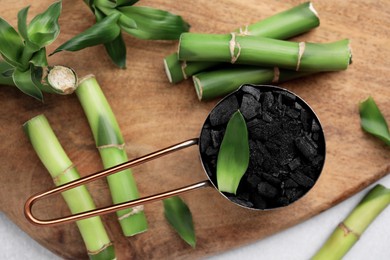 Fresh bamboo and charcoal on wooden board, flat lay