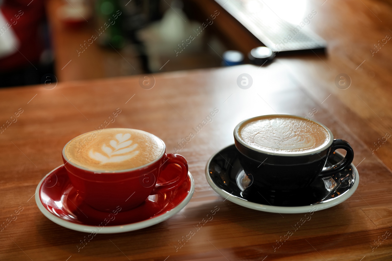 Photo of Cups of coffee on wooden counter in bar. Space for text