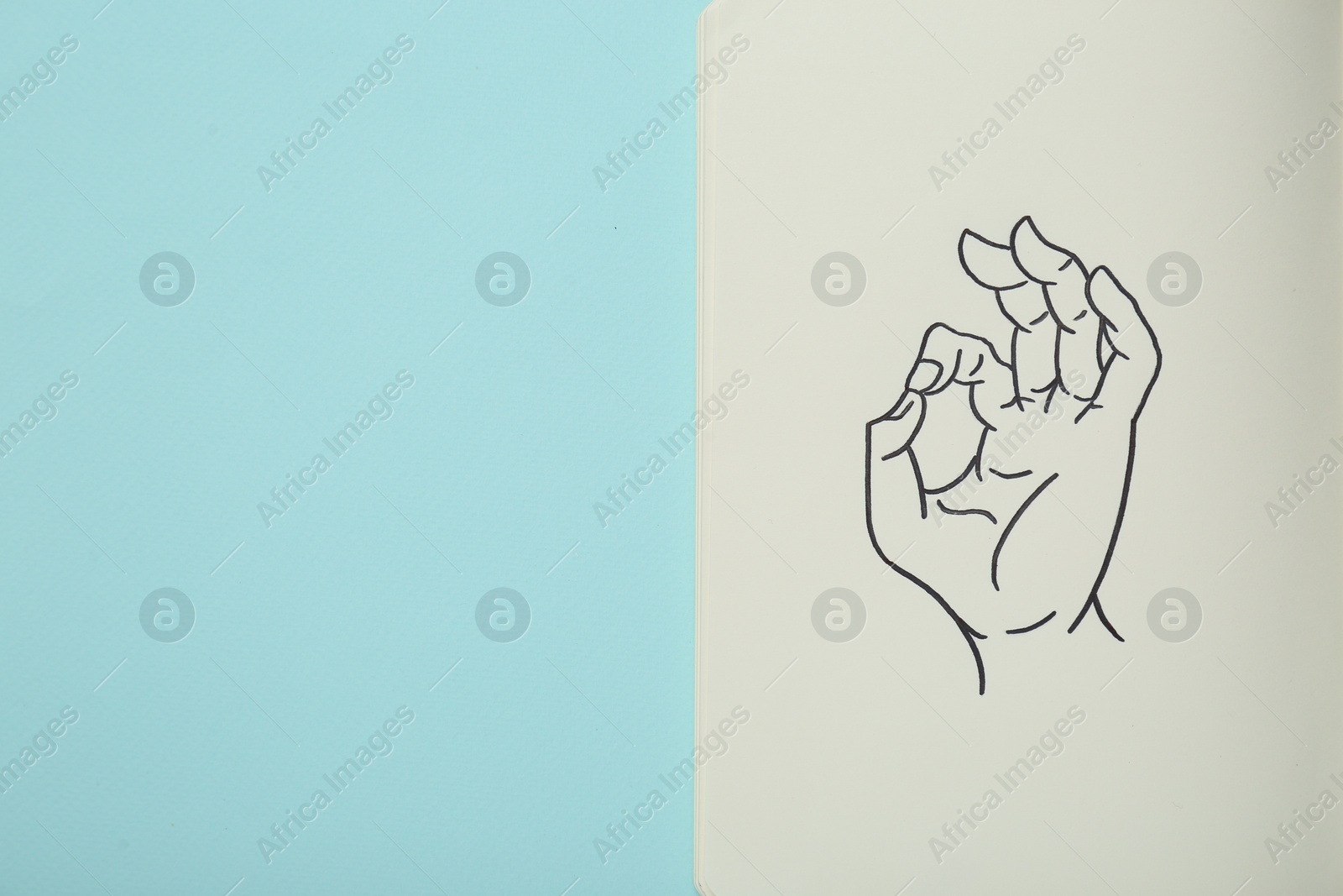 Photo of Notebook with drawing of hand showing okay gesture on light turquoise background, top view. Space for text