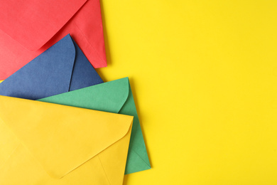 Photo of Colorful paper envelopes on yellow background, top view. Space for text