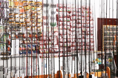 Photo of Stand with different fishing rods in sports shop