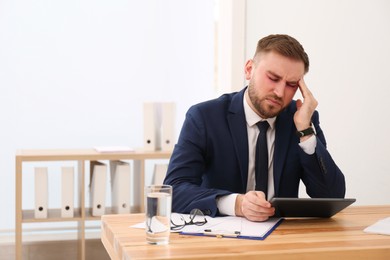 Tired man with red eyes at workplace in office