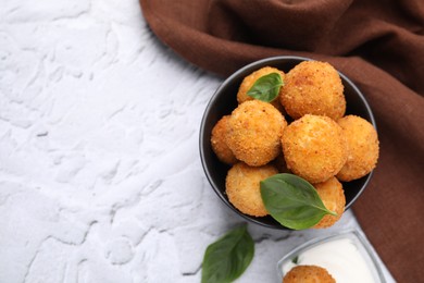 Photo of Bowl of delicious fried tofu balls with basil on white textured table, flat lay. Space for text