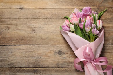 Photo of Beautiful bouquet of colorful tulip flowers on wooden table, top view. Space for text