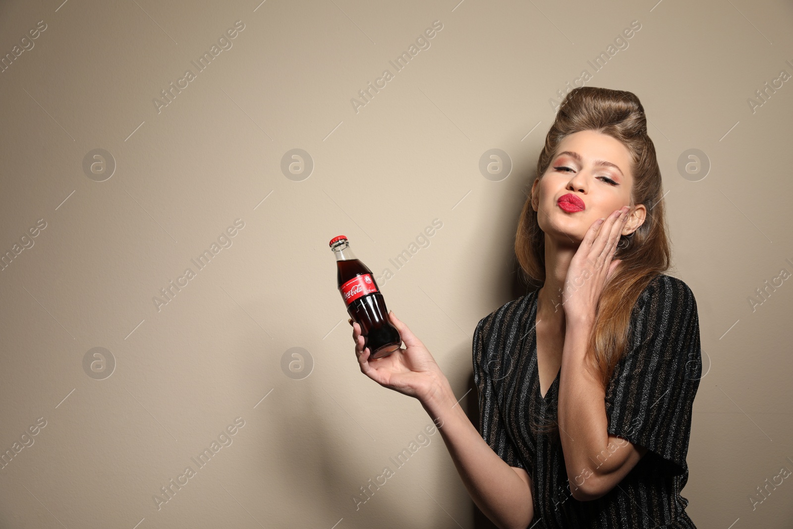 Photo of MYKOLAIV, UKRAINE - NOVEMBER 28, 2018: Young woman with bottle of Coca-Cola on color background, space for text