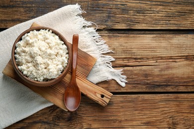Delicious fresh cottage cheese on wooden table, flat lay. Space for text