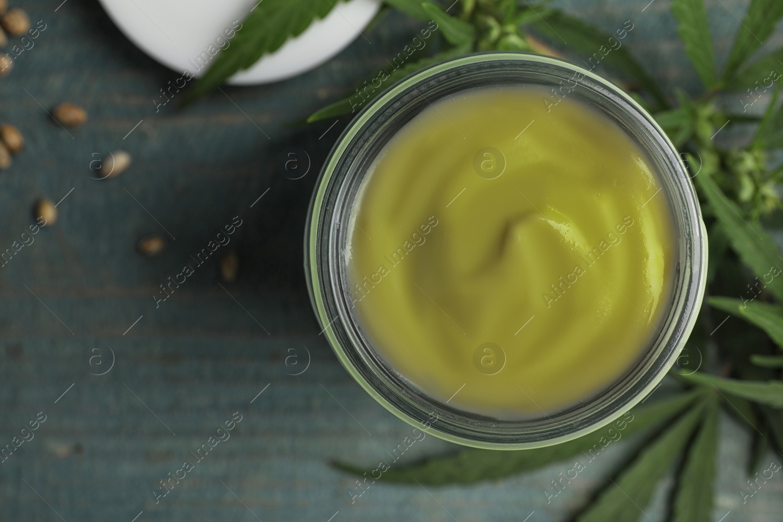 Photo of Jar of hemp cream on blue wooden table, flat lay. Organic cosmetics