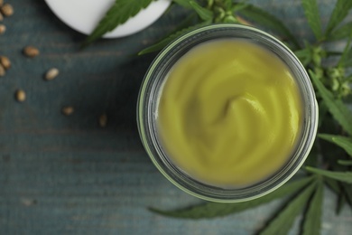 Jar of hemp cream on blue wooden table, flat lay. Organic cosmetics