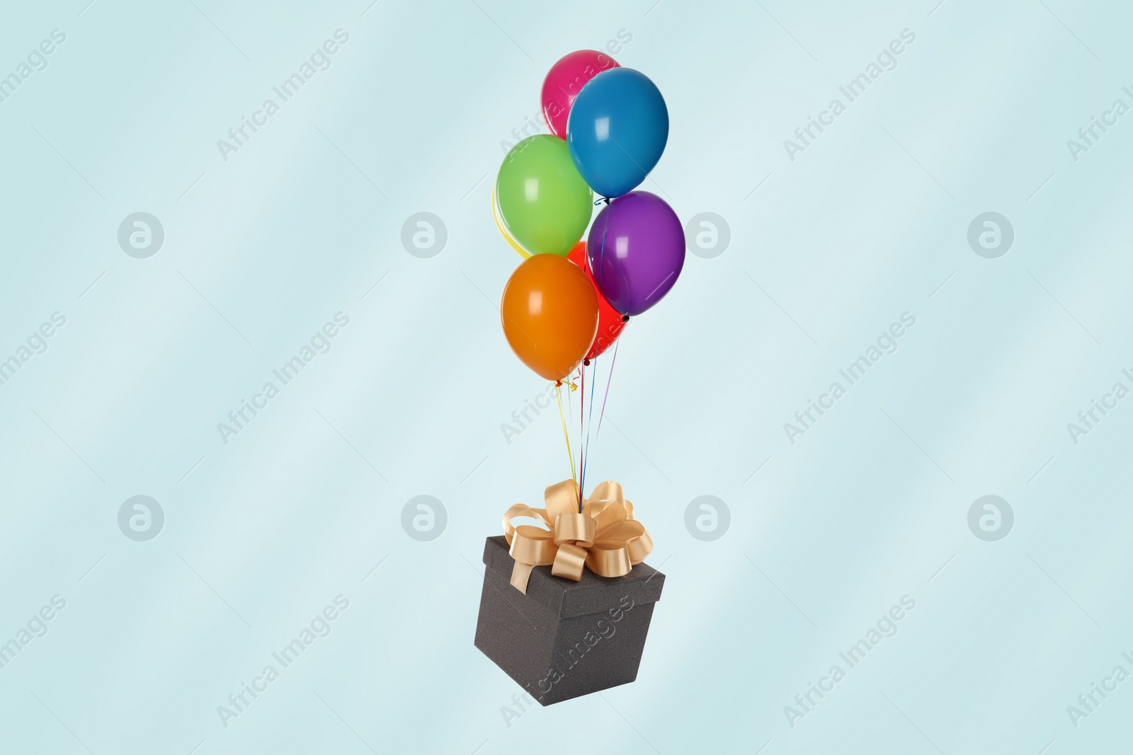 Image of Many balloons tied to gift box on light blue background