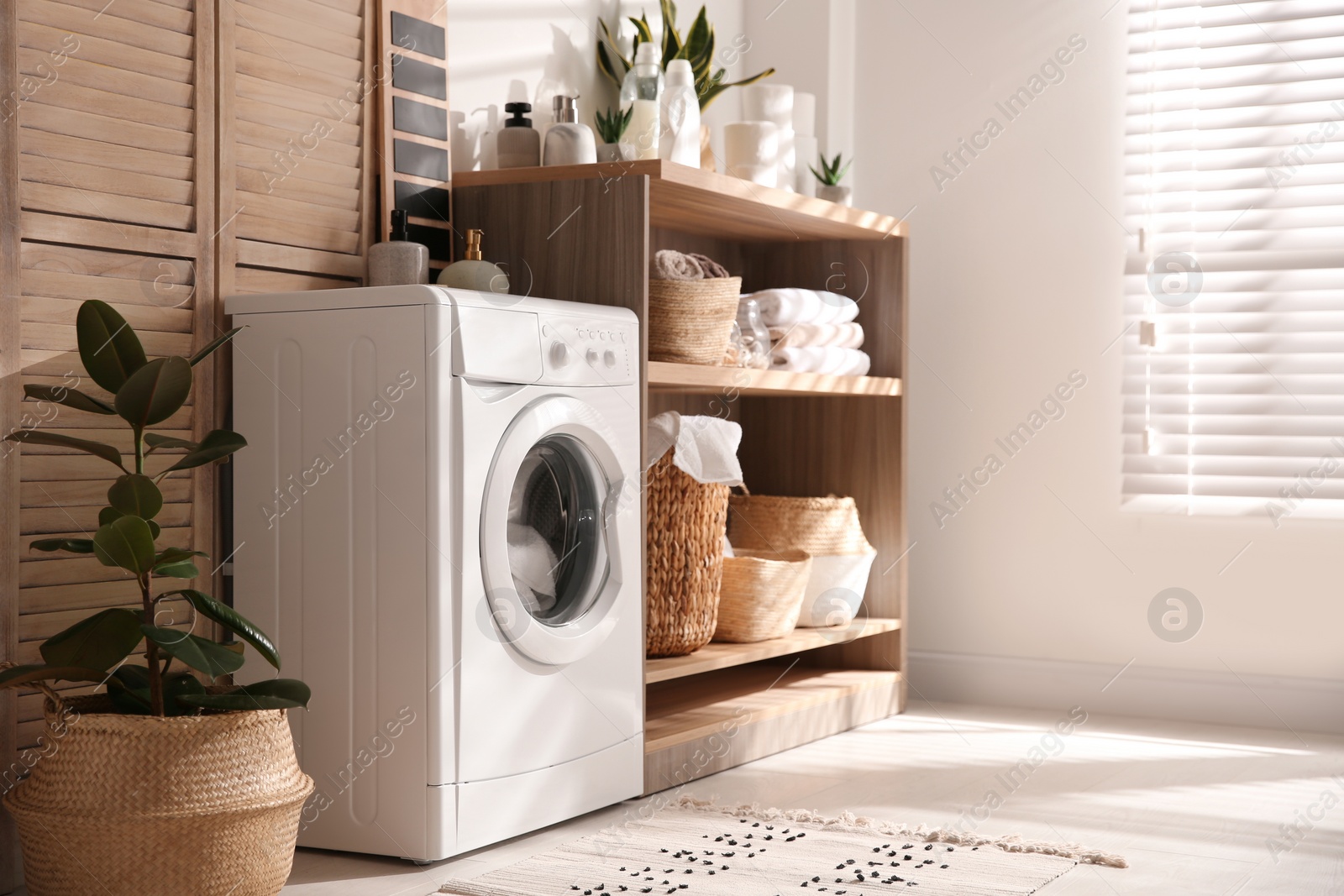 Photo of Modern washing machine and shelving unit in laundry room interior