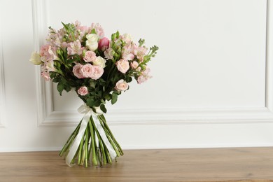 Photo of Beautiful bouquet of fresh flowers on wooden table near white wall, space for text