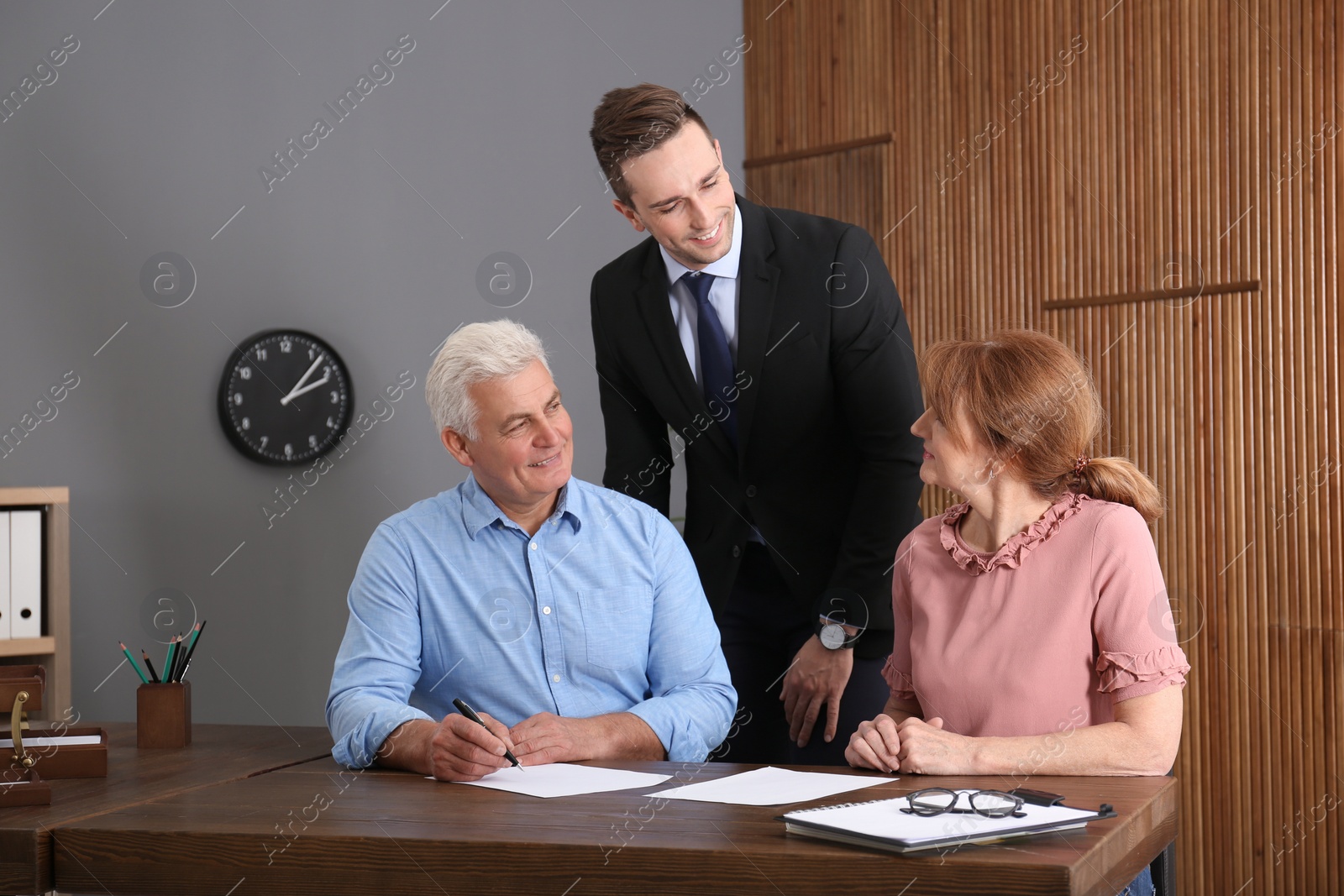 Photo of Young lawyer consulting senior couple in office