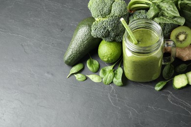 Photo of Delicious green juice and fresh ingredients on black table, space for text