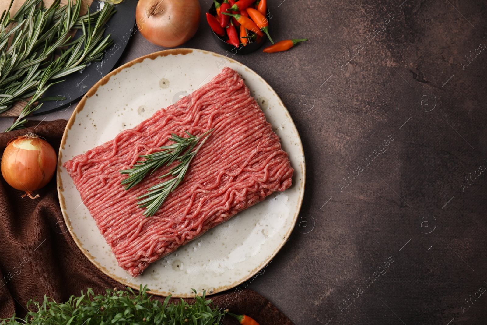 Photo of Flat lay composition with fresh raw ground meat, herbs and products on brown textured table. Space for text