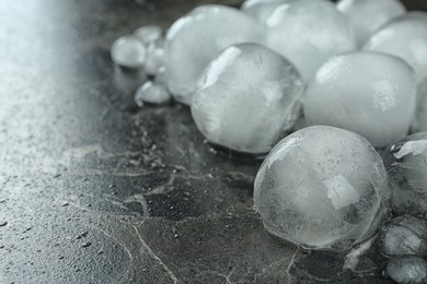 Photo of Many frozen ice balls on black marble table, closeup. Space for text