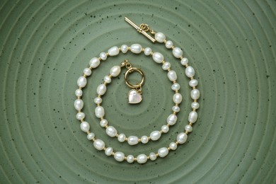 Photo of Elegant pearl necklace on olive textured background, top view