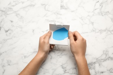 Photo of Woman with package of oil blotting tissues at white marble table, top view. Mattifying wipes