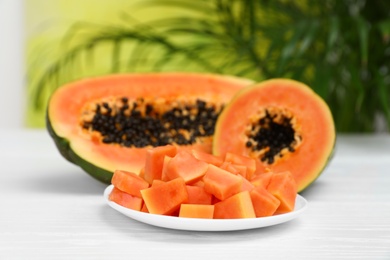 Fresh juicy papayas on white table against blurred background