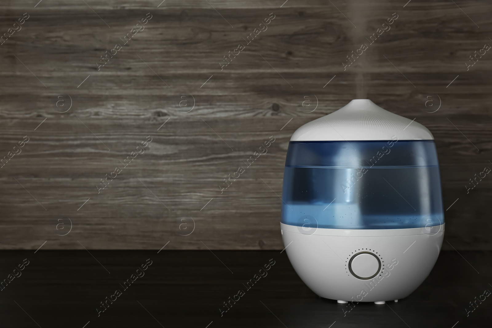 Photo of Modern air humidifier on wooden table. Space for text