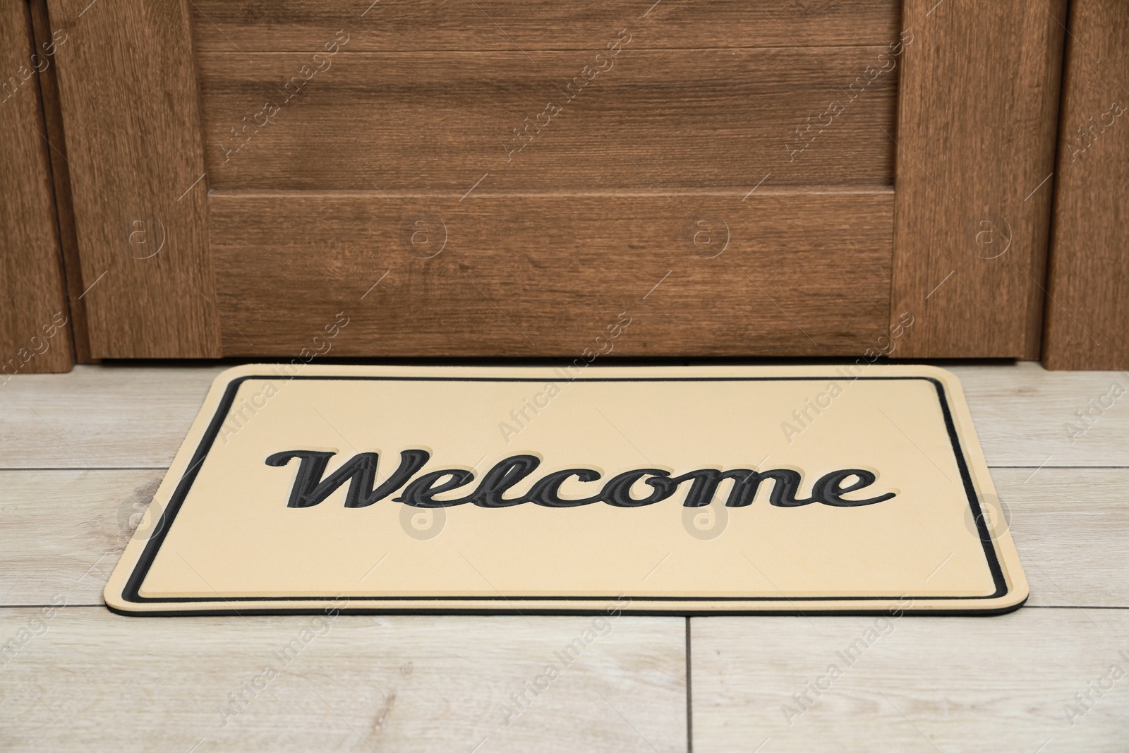 Photo of Beautiful beige doormat with word Welcome on floor near entrance