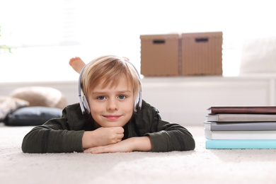 Photo of Cute little boy with headphones listening to audiobook at home