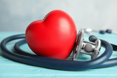 Stethoscope and red heart on wooden table. Cardiology concept