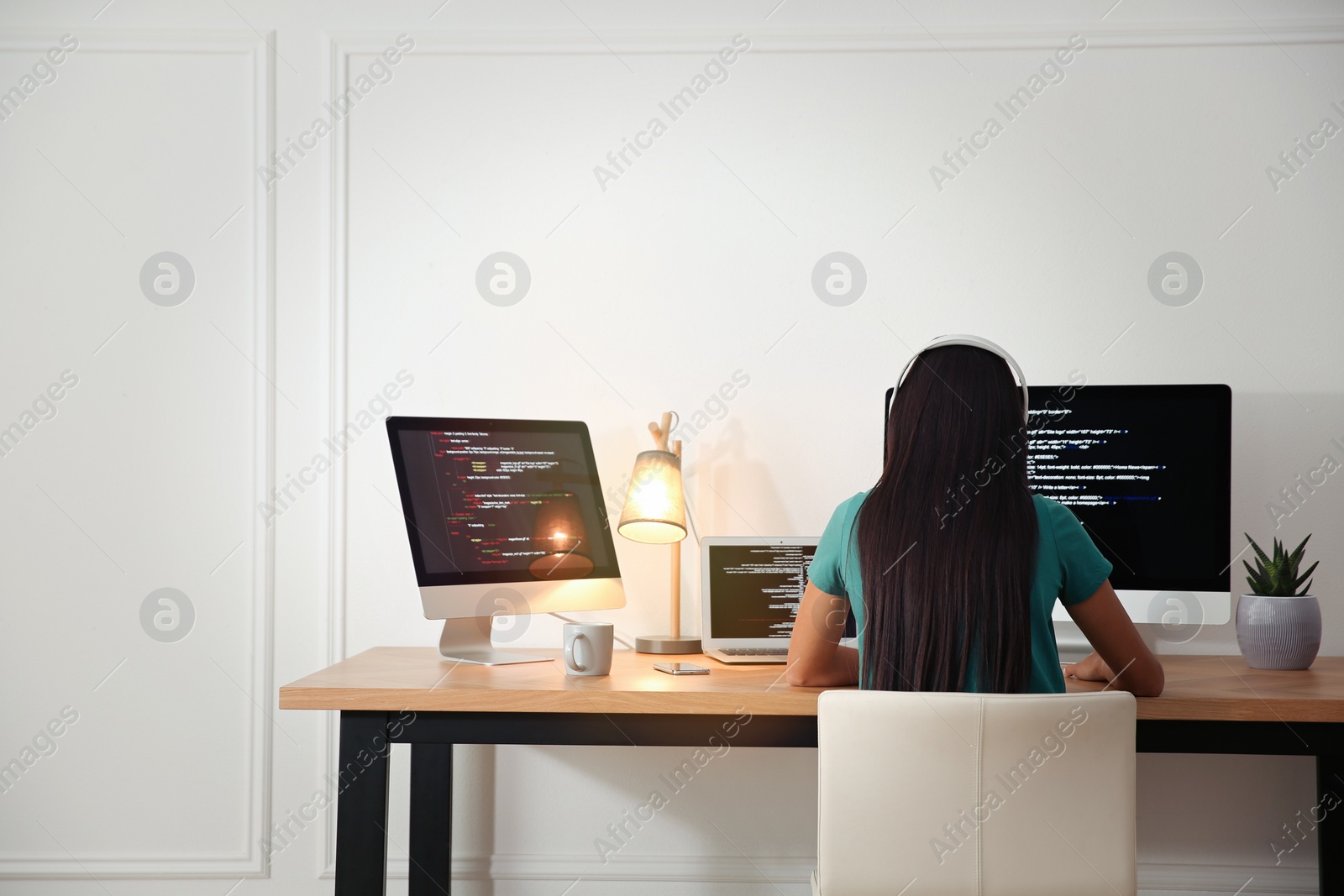 Photo of Programmer with headphones working at desk in office