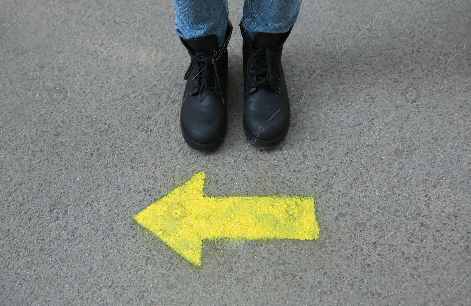 Photo of Person standing near arrow on asphalt, closeup