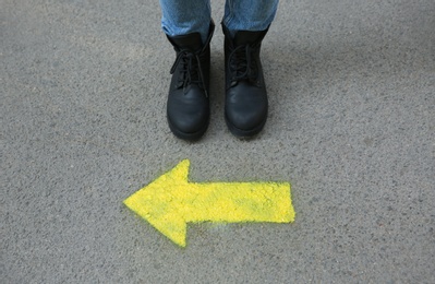 Photo of Person standing near arrow on asphalt, closeup