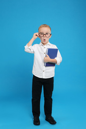 Photo of Full length portrait of cute little boy with book on light blue background