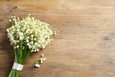 Photo of Beautiful lily of the valley bouquet on wooden table, top view. Space for text