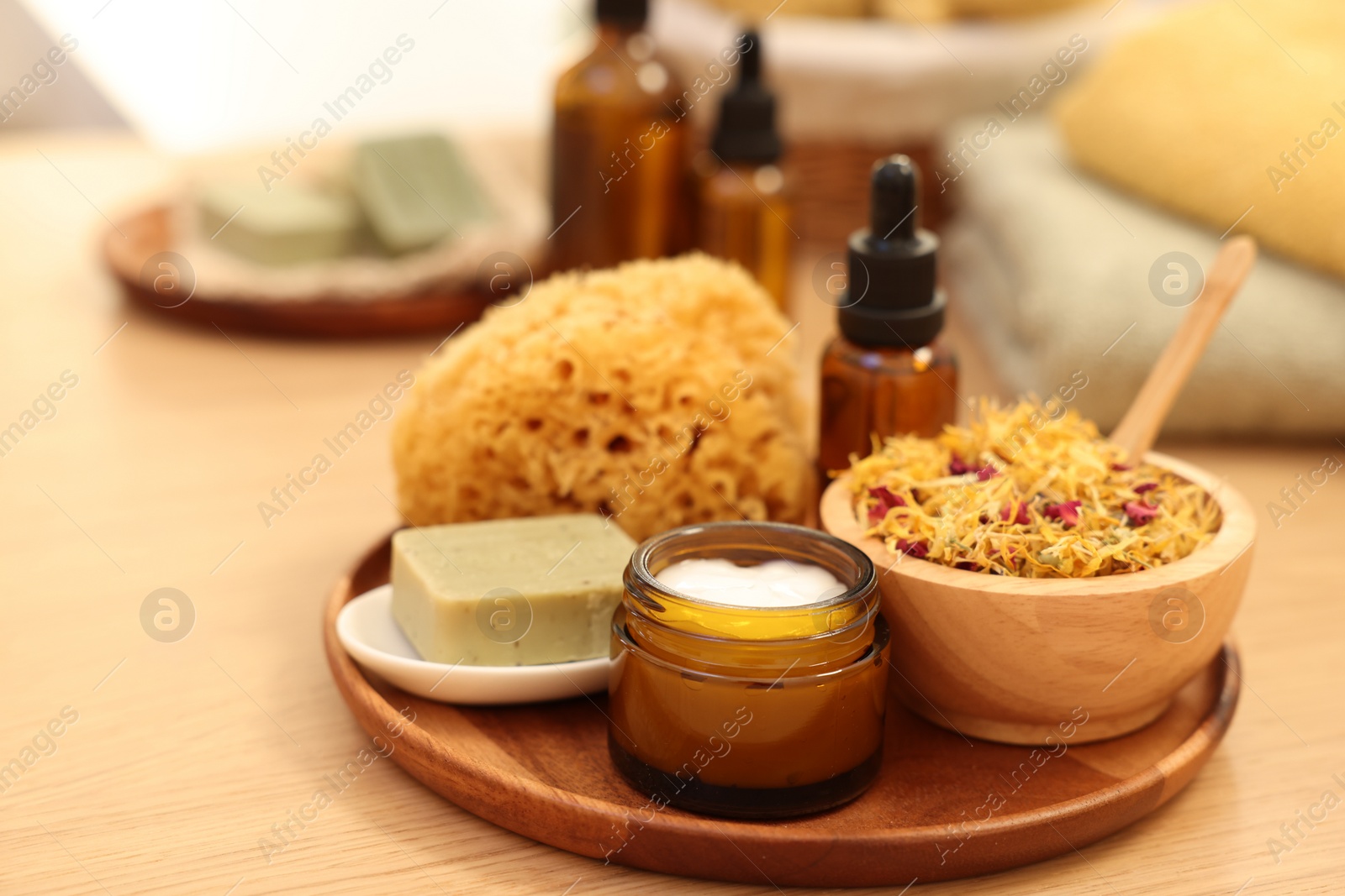 Photo of Dry flowers, loofah, soap bar, bottle of essential oil and jar with cream on wooden table, closeup and space for text. Spa time