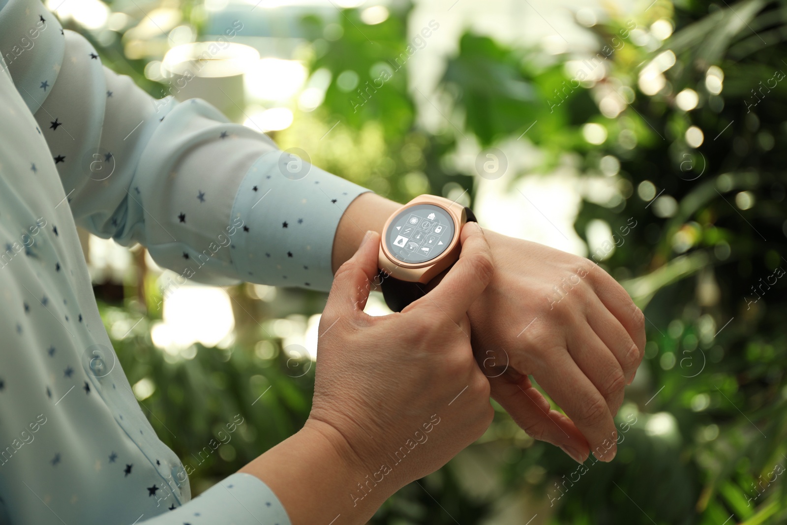 Image of Woman setting smart home control system via smartwatch outdoors, closeup. App interface with icons on display