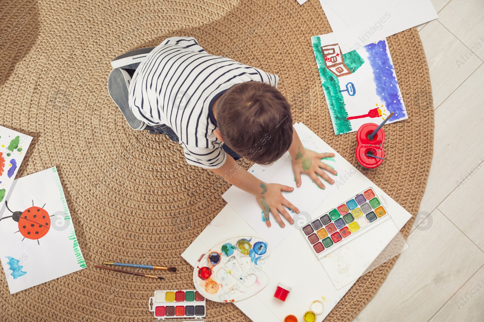 Photo of Little child painting on floor at home, top view