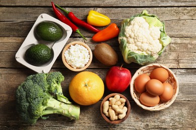 Photo of Healthy meal. Different vegetables and raw eggs on wooden table, flat lay