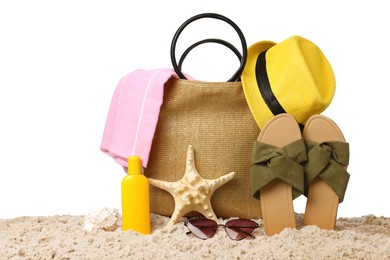 Stylish bag with beach accessories on sand against white background