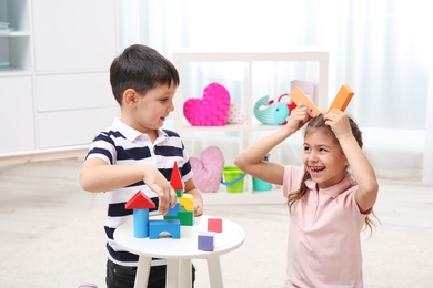 Cute children playing with colorful blocks at home