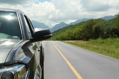 Photo of Car driving on asphalt road near mountains, closeup. Space for text