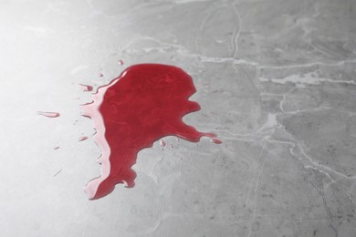 Photo of Spot of spilled juice on grey surface, closeup. Space for text