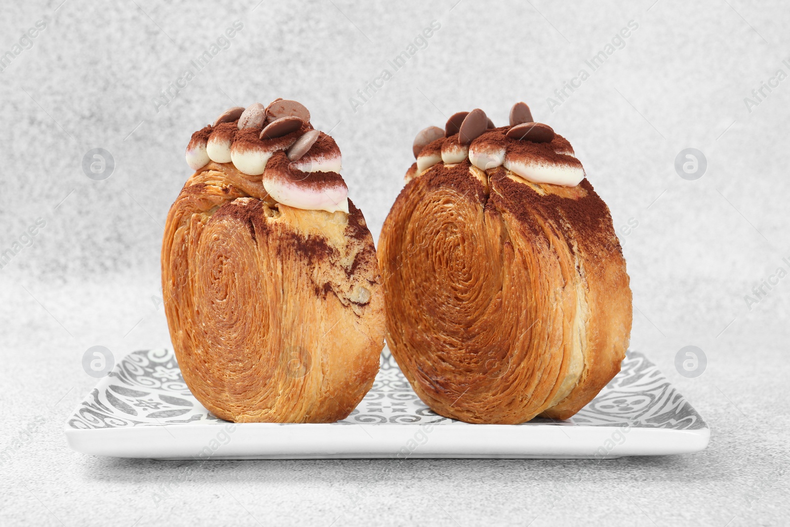 Photo of Supreme croissants with chocolate chips and cream on grey background, closeup. Tasty puff pastry