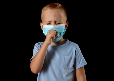 Photo of Little boy in medical mask on black background. Virus protection