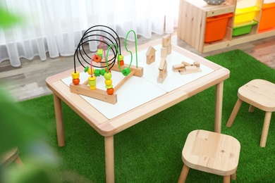 Photo of Stylish playroom interior with toys and modern wooden furniture