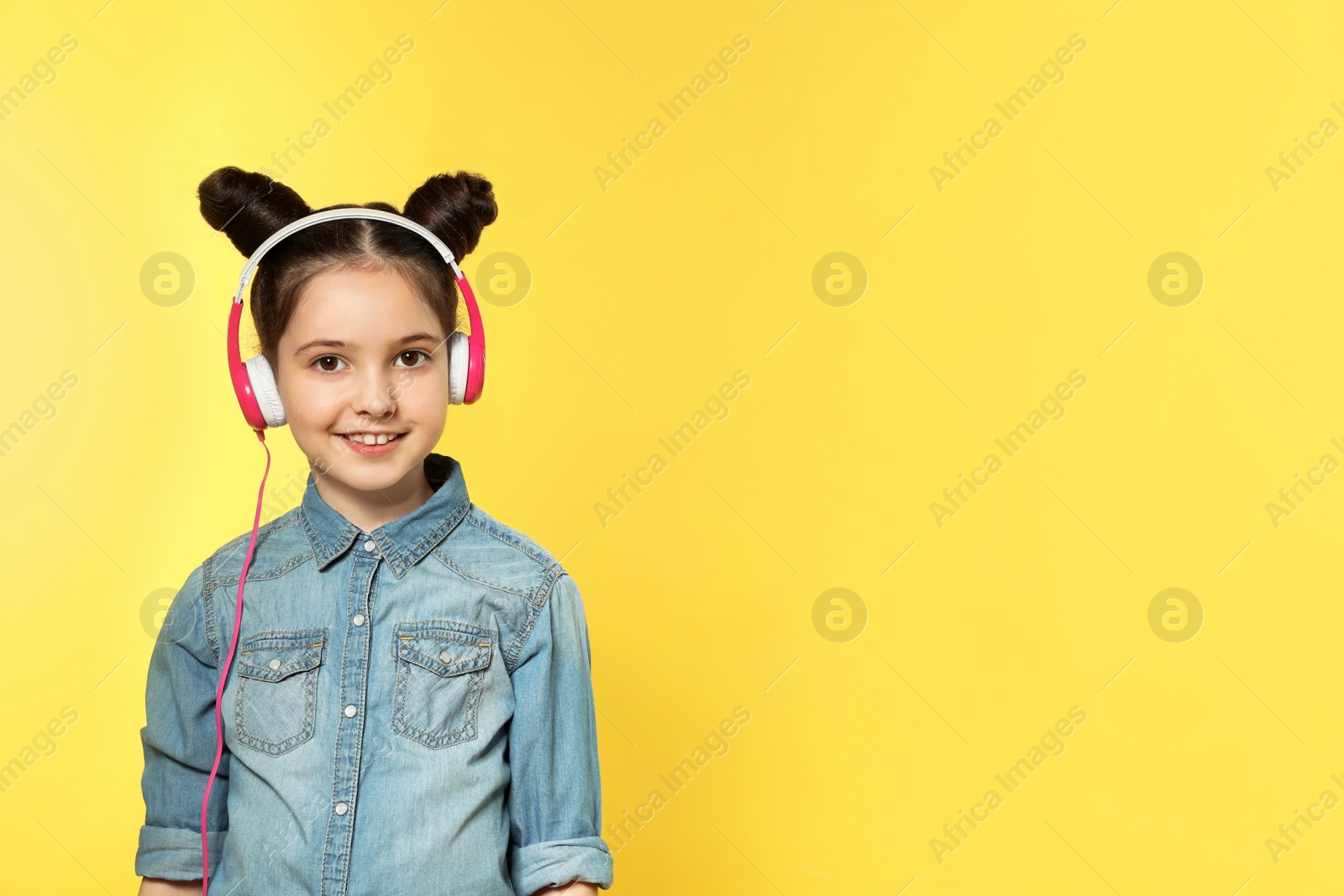 Photo of Cute girl enjoying music in headphones on color background. Space for text