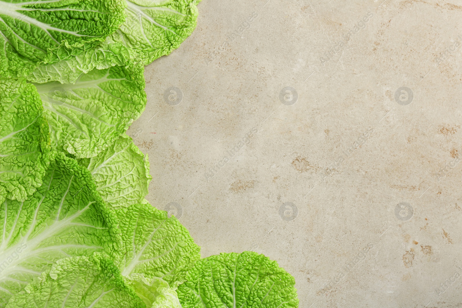 Photo of Fresh Chinese cabbage leaves on gray textured table, top view. Space for text