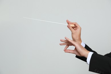 Photo of Professional conductor with baton on light grey background, closeup. Space for text